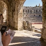 Arènes de Nîmes durée visite : touriste avec audioguide dans l’amphithéâtre